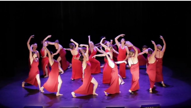 Groupe d'élèves adultes en robes rouges lors du spectacle de fin d'année du cours de danse
