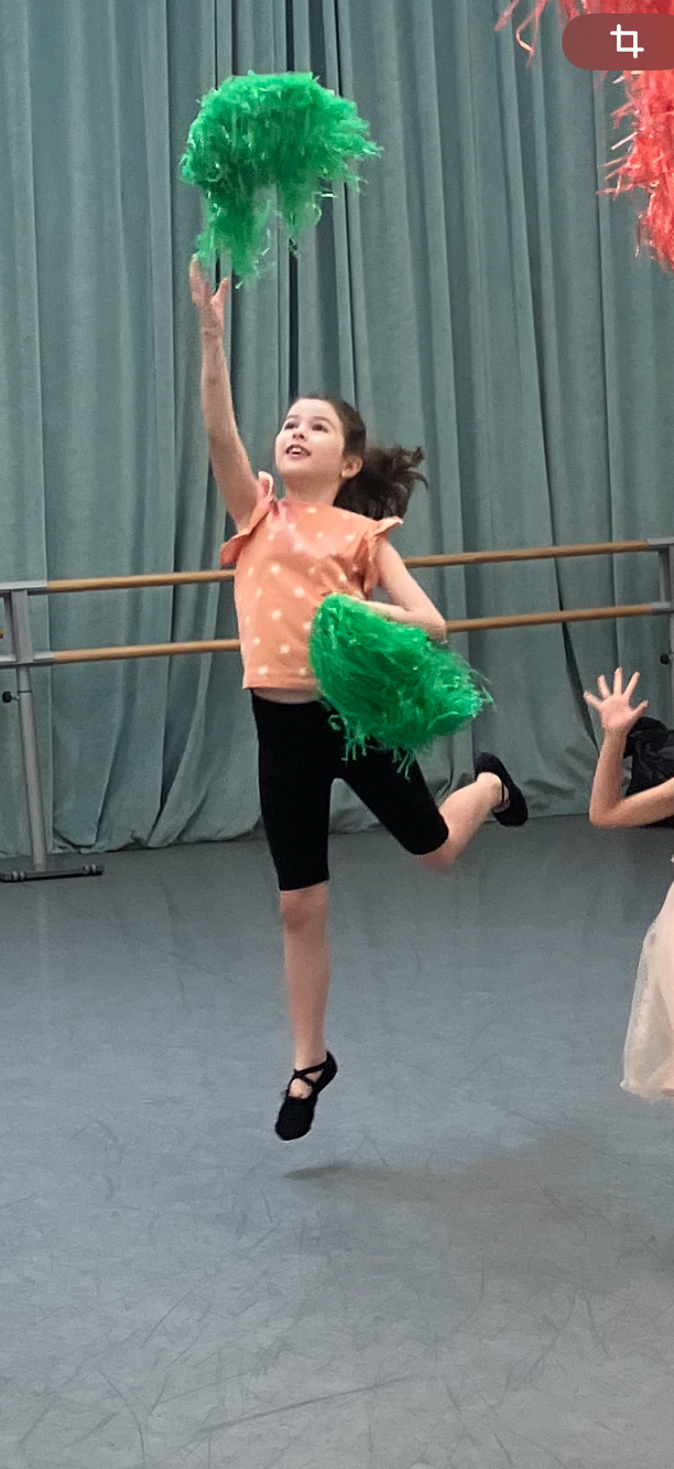 Enfant en plein saut avec des pompons pendant un cours de danse à Paris 18
