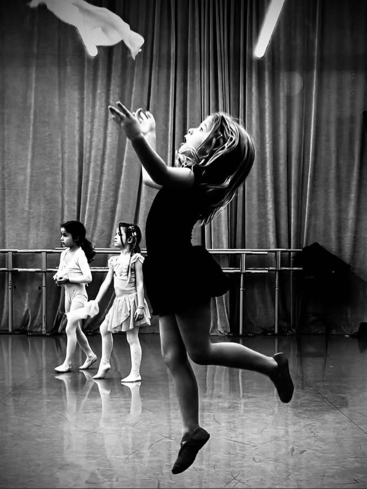 Photo noir et blanc d'une enfant en saut avec un foulard pendant le cours de danse