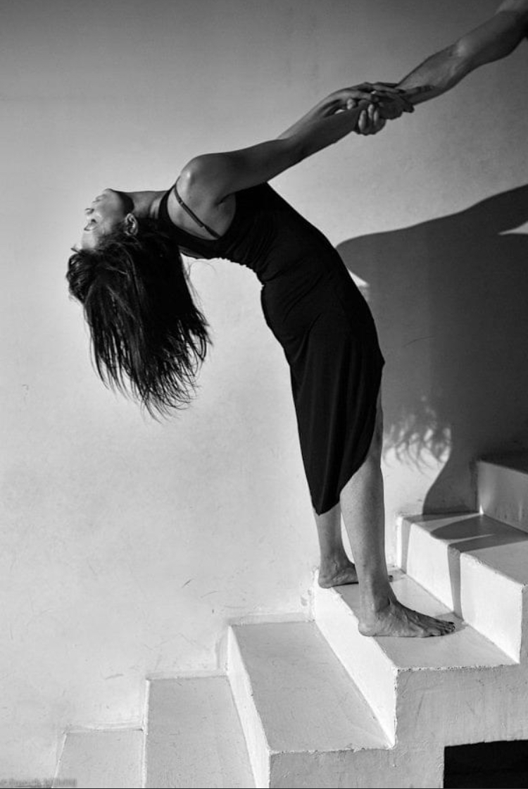 Danseuse en cambré sur un escalier blanc, main tendue