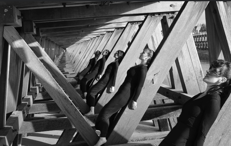 Groupe de danseuses alignées sous une structure de bois