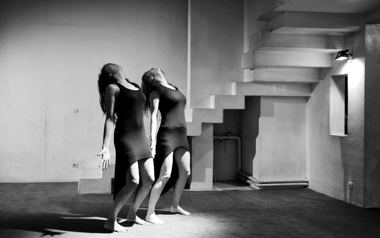 Duo de danseuses dos à dos dans un espace de béton